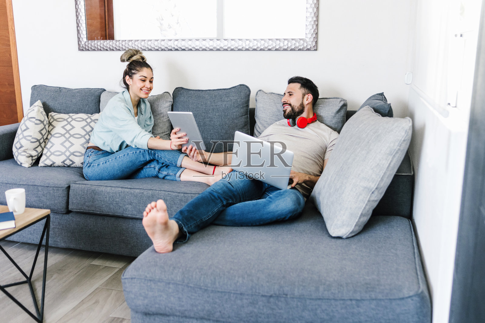 一对年轻的成年男女在拉丁美洲墨西哥的萨法家中使用笔记本电脑和数字平板电脑照片摄影图片