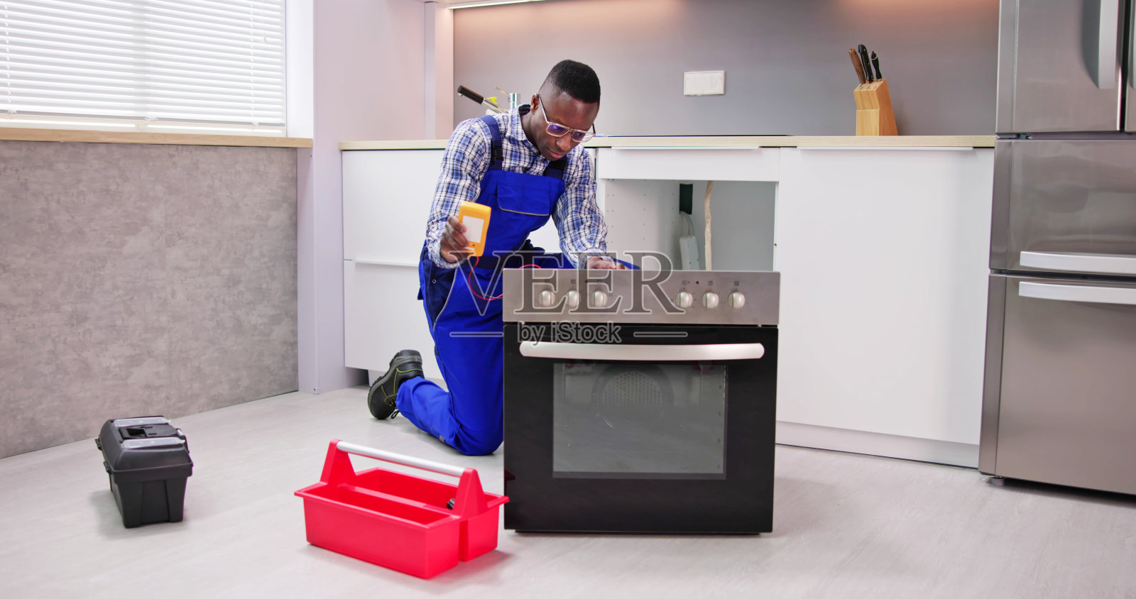 年轻的修理工正在修理烤箱照片摄影图片