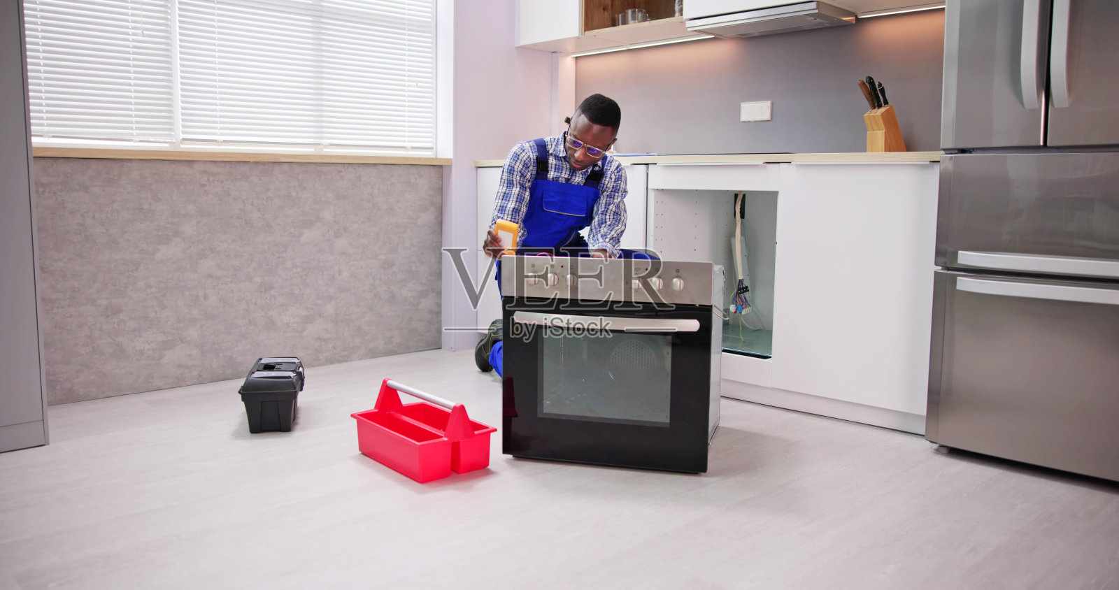 年轻的修理工正在修理烤箱照片摄影图片