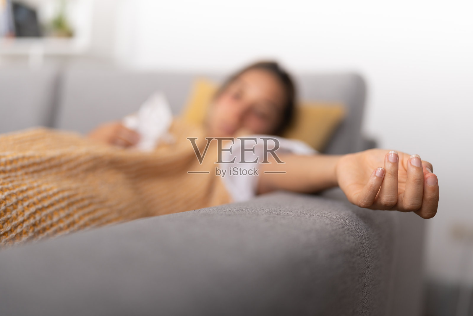 发高烧的年轻女士，手臂伸开躺在沙发上照片摄影图片