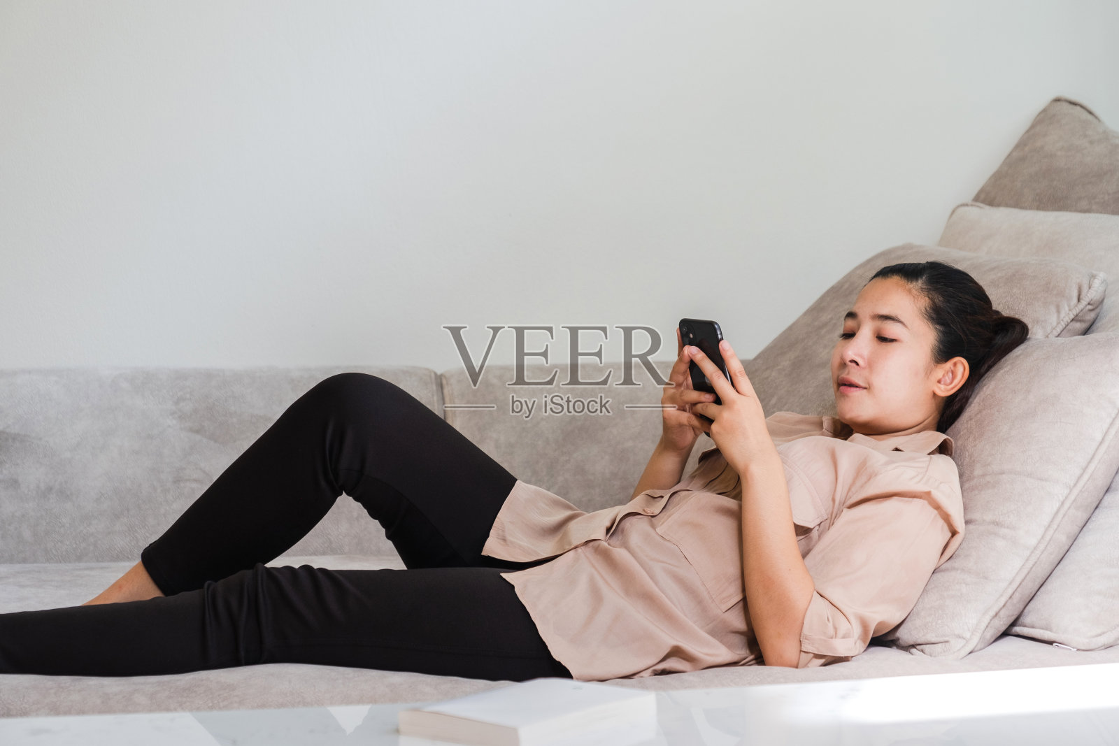 快乐的年轻亚洲女性在家工作，在笔记本电脑上工作和放松，书，手机社交网络照片摄影图片