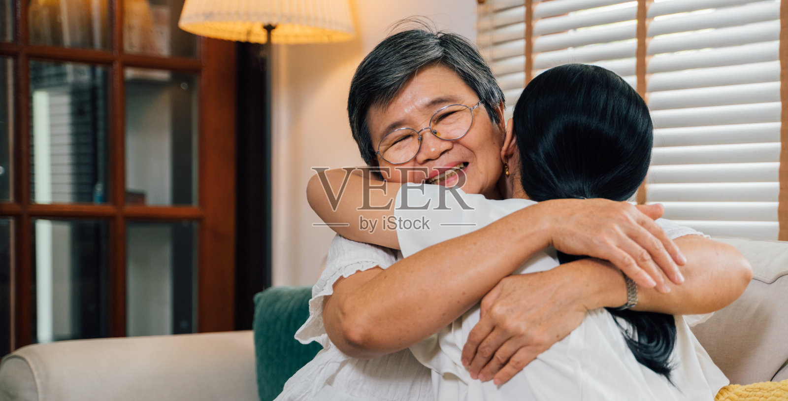 亚洲女儿在沙发上拥抱妈妈照片摄影图片