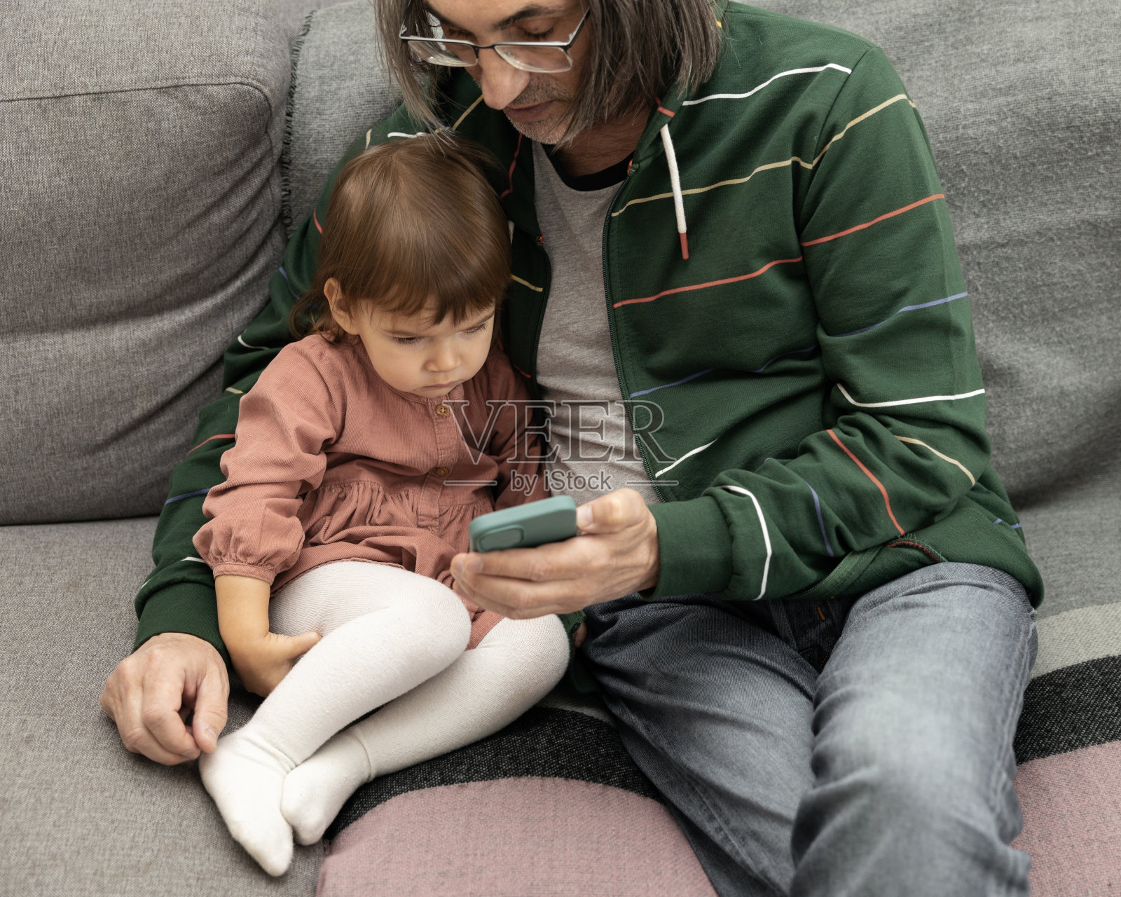 爷爷和孙女坐在家里的沙发上看手机照片摄影图片