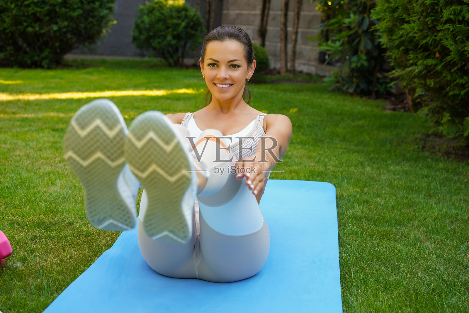 迷人的苗条女孩在运动服做腹肌锻炼户外。健康的生活方式。照片摄影图片