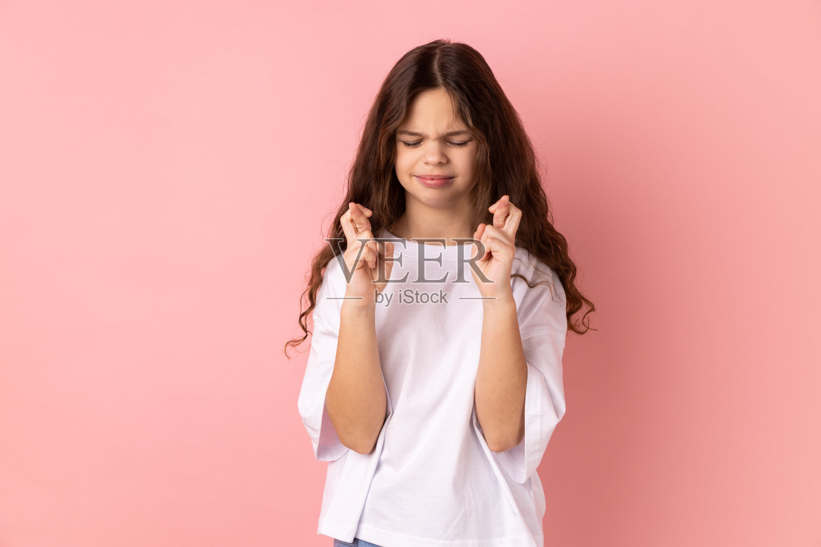 小女孩交叉手指希望好运，许愿，仪式，闭着眼睛站着。照片摄影图片