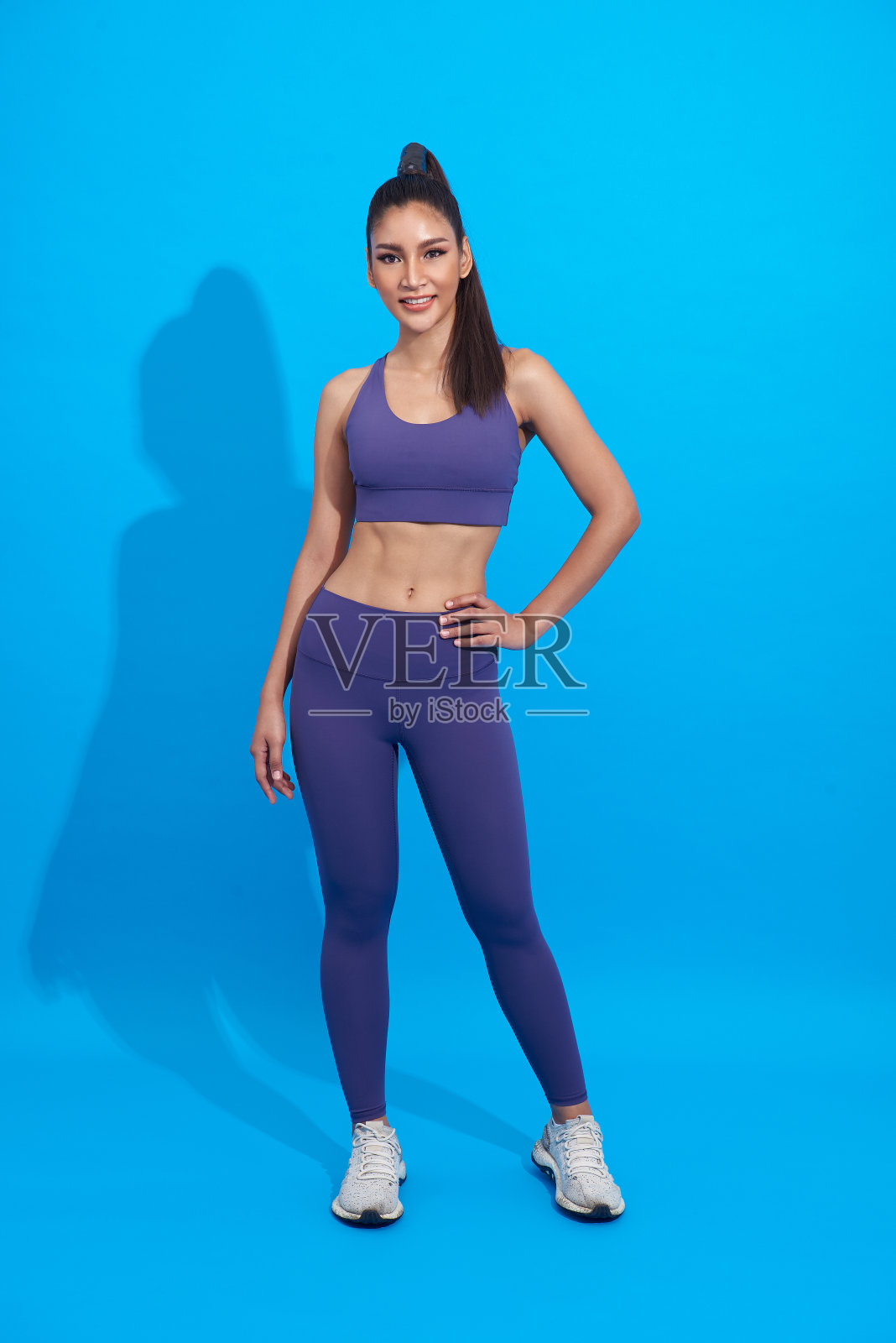 快乐的亚洲运动女性做运动穿着运动服在蓝色的背景。健康健美的女性观念。照片摄影图片
