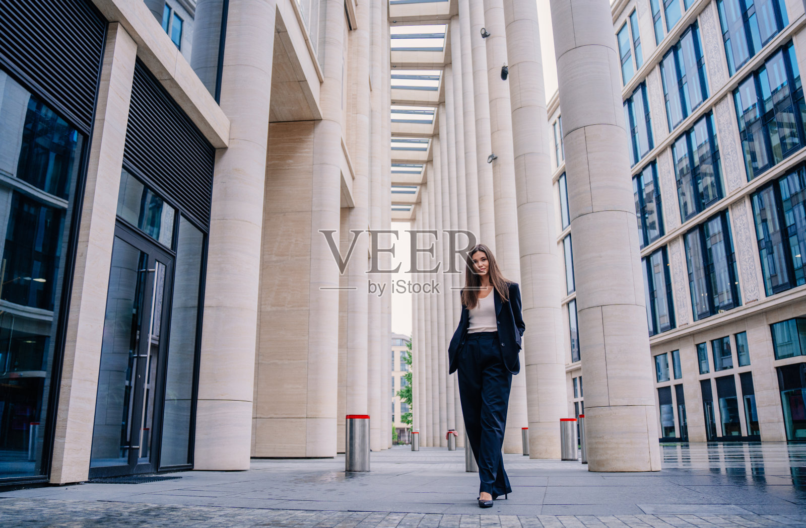 年轻的黑发女商人站在外面看猫相机。穿着黑色西装的漂亮亚洲女人去办公室。成功的管理者对抗商业中心。金融人。律师去法庭。照片摄影图片