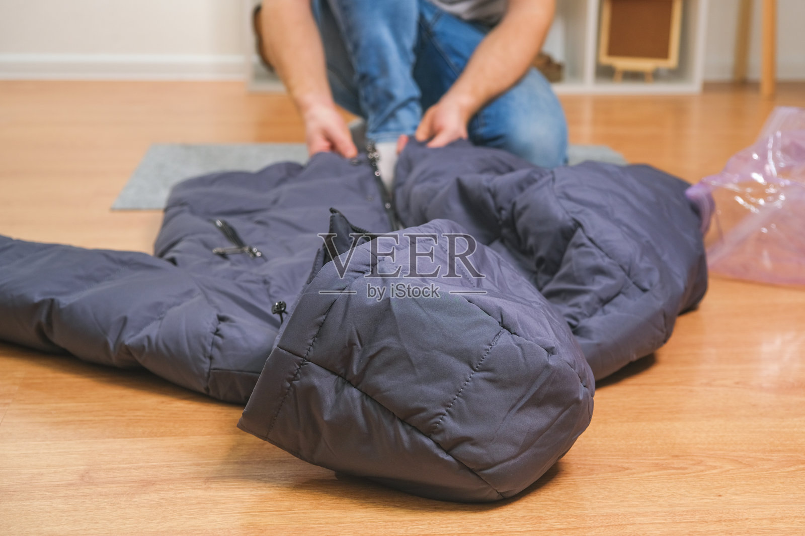 一名男子将冬季夹克折叠起来，放入真空袋中，以备季节性储存。照片摄影图片