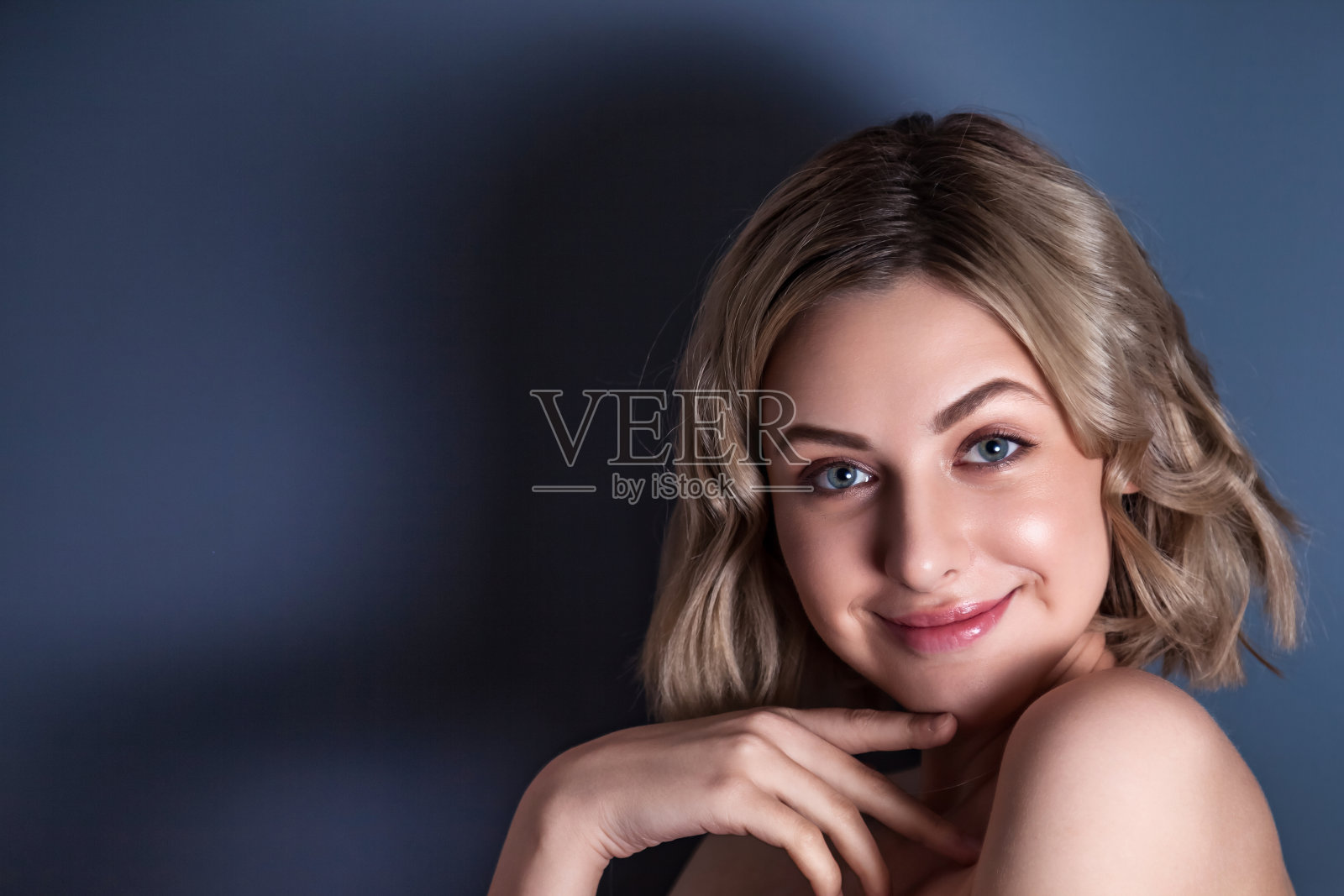 特写肖像调情漂亮微笑的女人，在深灰色的背景，看着相机。可爱的女士孤立在空白的工作室墙上的情感脸。人类情感的概念。复制文本空格照片摄影图片