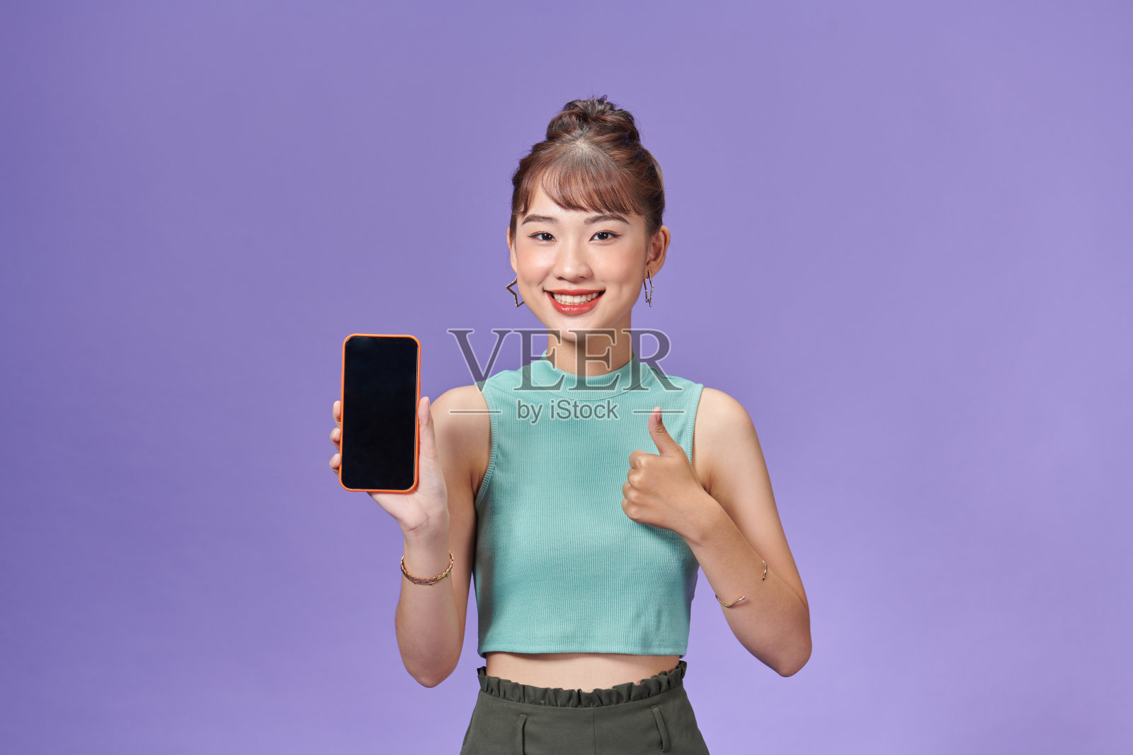 微笑的亚洲女性手持智能手机，手持黑色空白设备屏幕，显示拇指向上的手势照片摄影图片