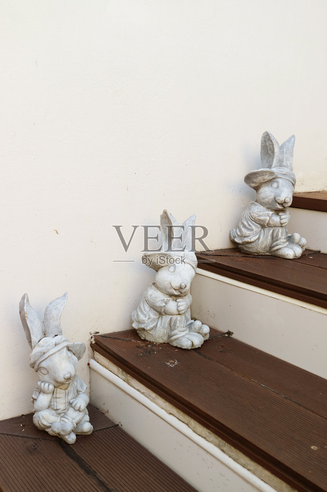木制台阶上的三个可爱的复活节兔子雕像照片摄影图片
