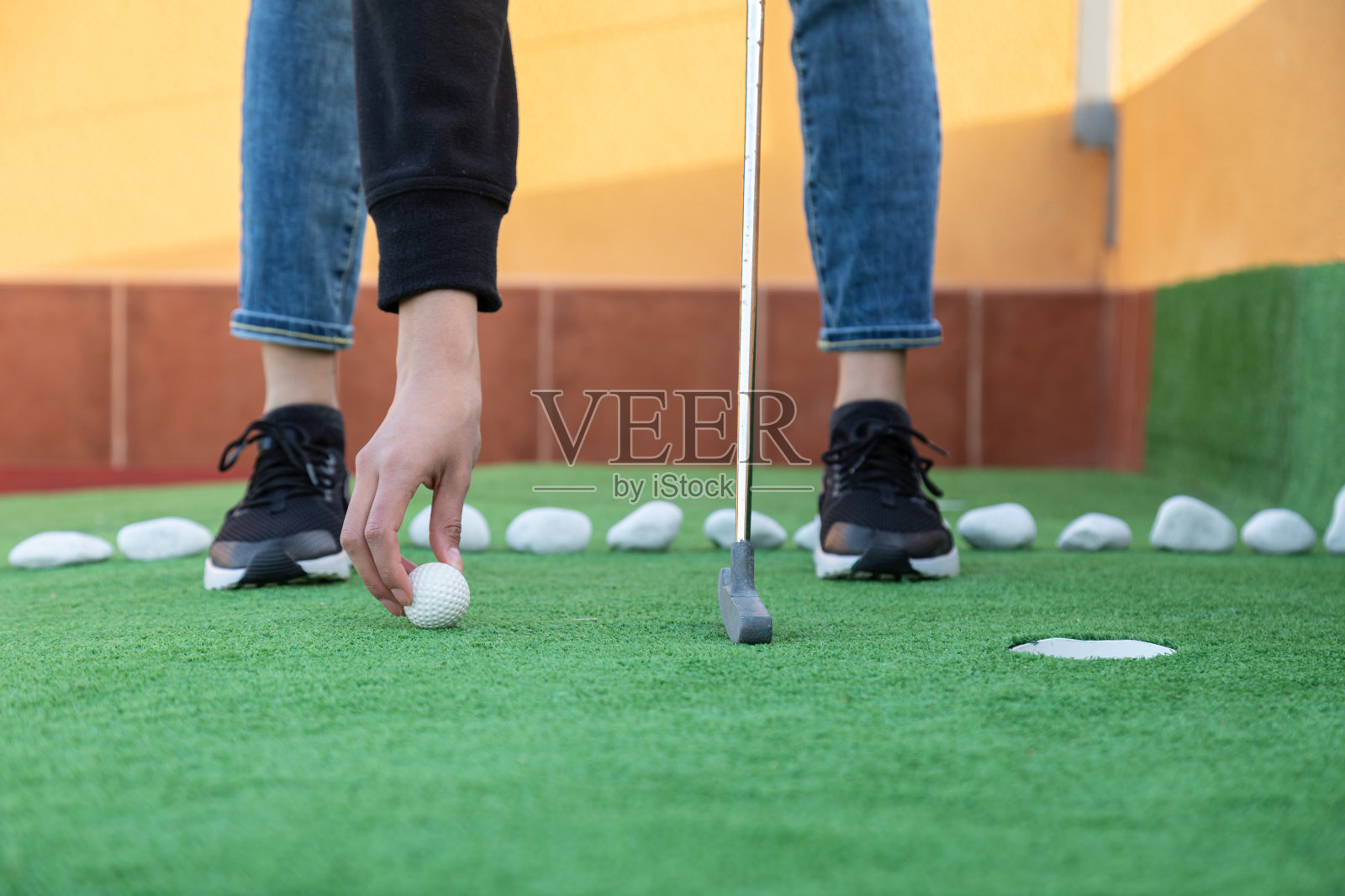 一个无法辨认的女人把高尔夫球放在地上玩迷你高尔夫球的特写照片摄影图片