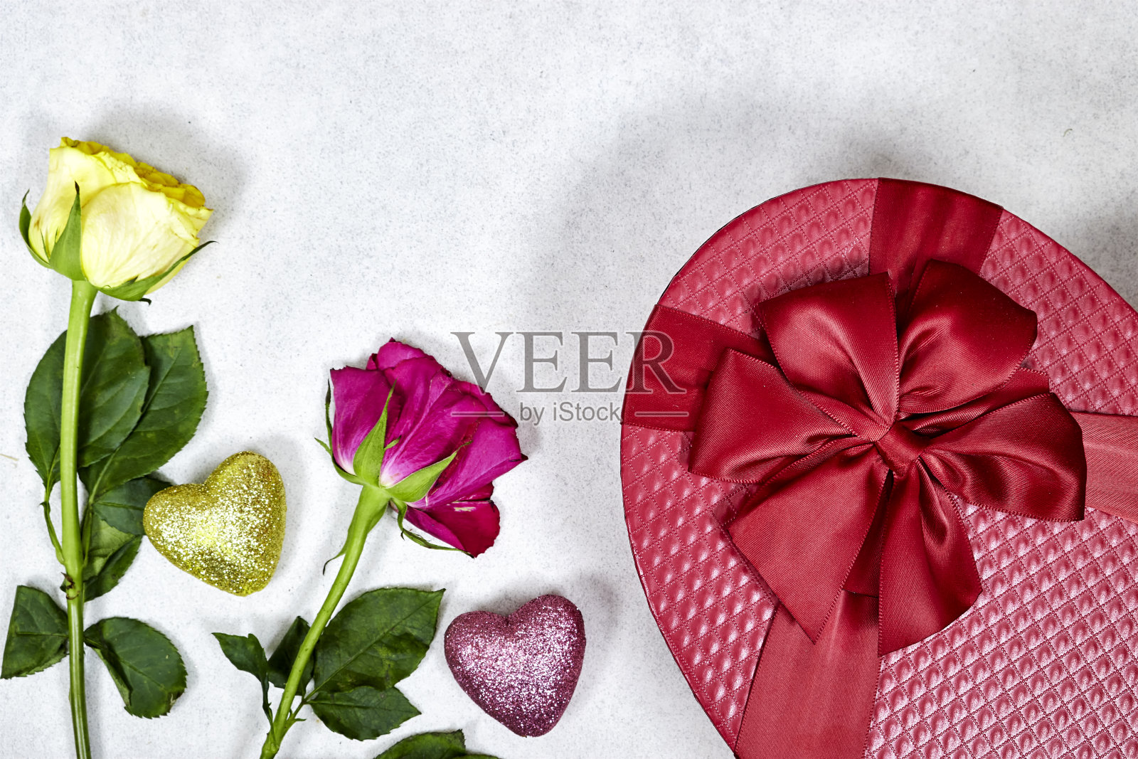关闭红色形状的礼盒与粉红色，黄色玫瑰孤立在灰色背景的节日照片摄影图片