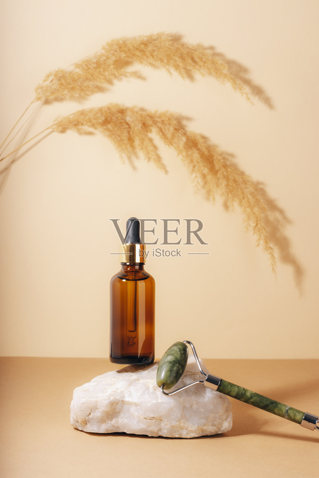 棕色化妆品精华瓶和玉石面部辊在天然石材平台上。天然护肤化妆品概念。特写镜头照片摄影图片