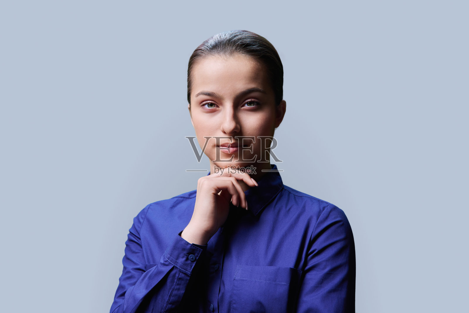 十几岁的女孩15、16岁的肖像，微笑着看着相机在灰色的背景照片摄影图片