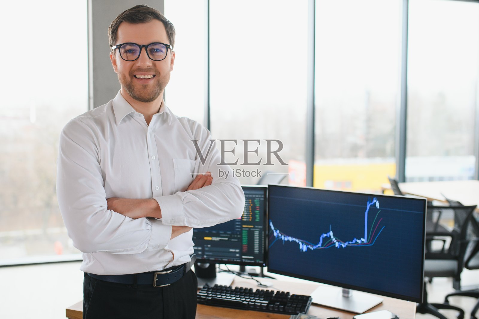 年轻的大胡子交易员在办公室的桌子上看着相机笑得开朗照片摄影图片