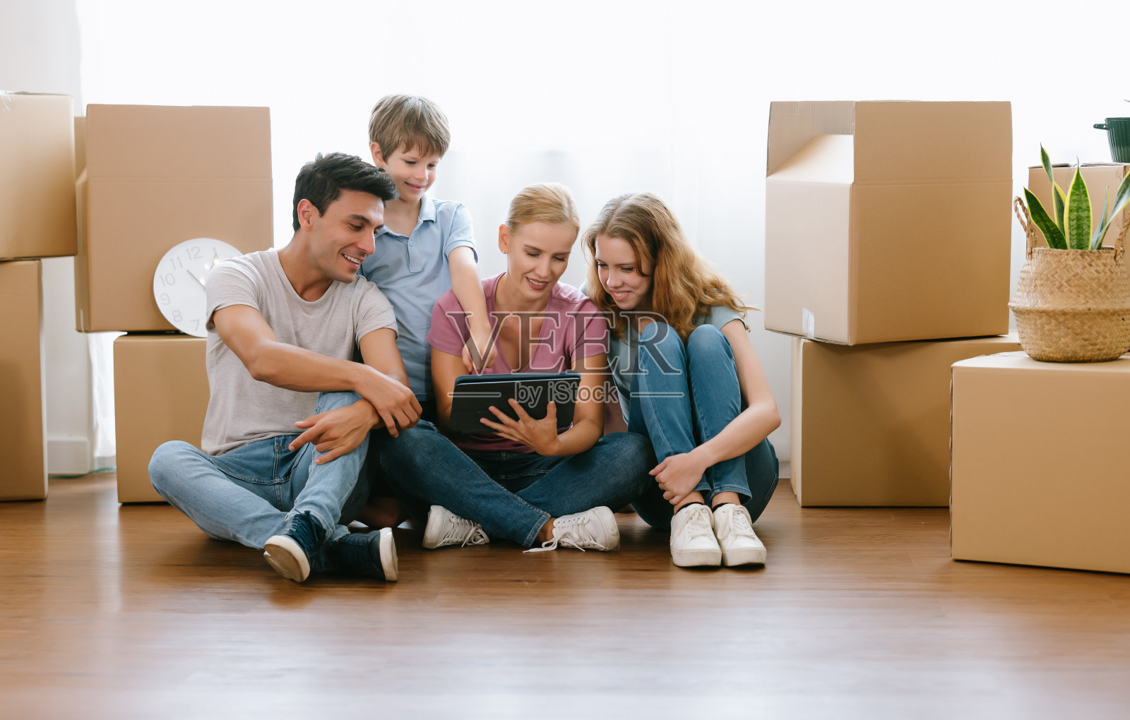 白人家庭父亲、母亲、女儿、儿子坐在地板上，用平板电脑在网上购物，选择和订购家具，在家里讨论装饰。生活方式幸福家庭一起搬迁照片摄影图片