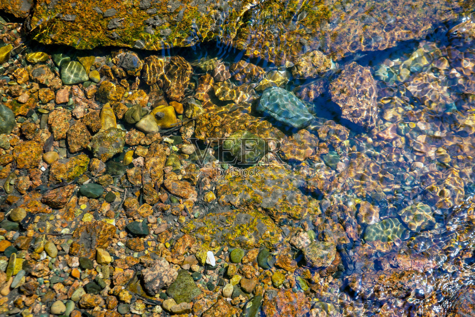小石头在河底下一层清澈的水。背景来自石头。水和石头的纹理。照片摄影图片