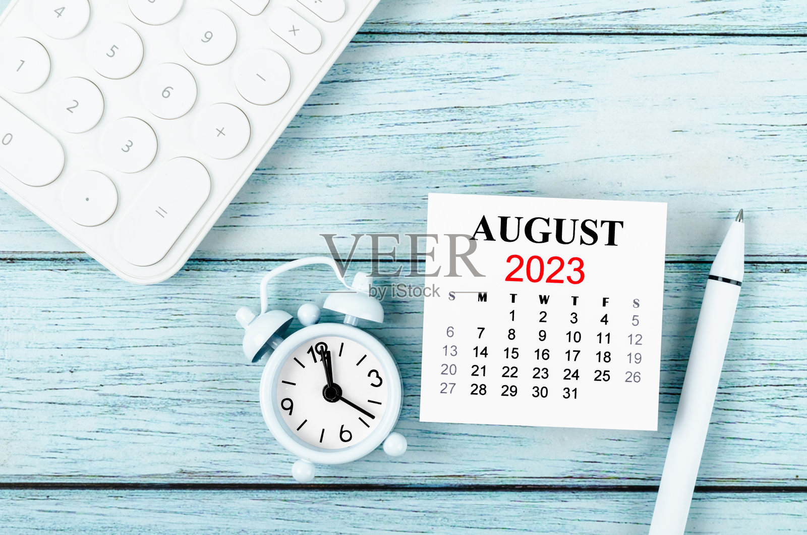 2023年8月日历年和闹钟与计算器在蓝色木制背景。照片摄影图片