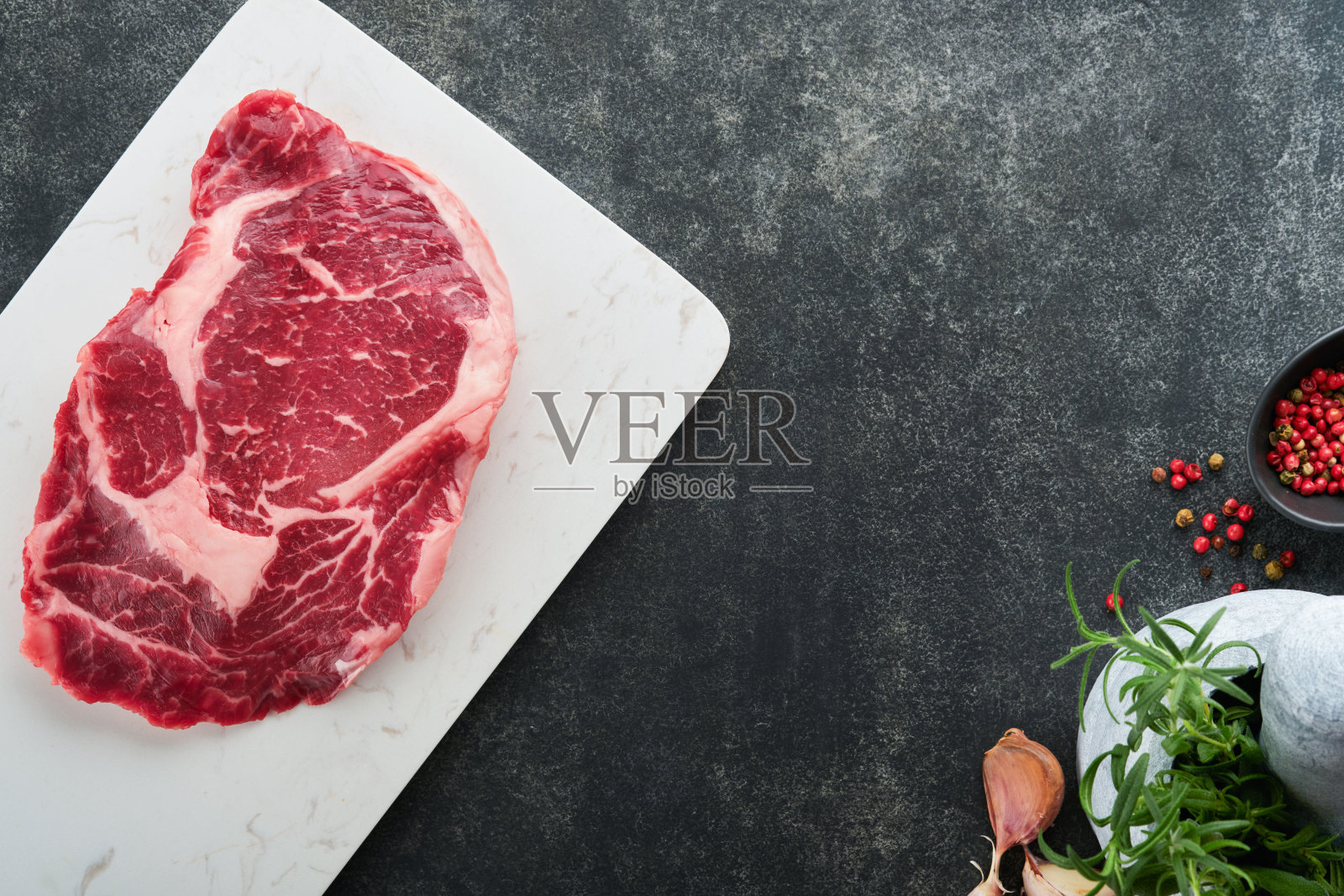 生的肋眼牛排或肋眼牛排。新鲜的大理石肉肋眼黑安格斯和调味胡椒，迷迭香，百里香和盐在古老的木制乡村背景。俯视图和复制空间。照片摄影图片