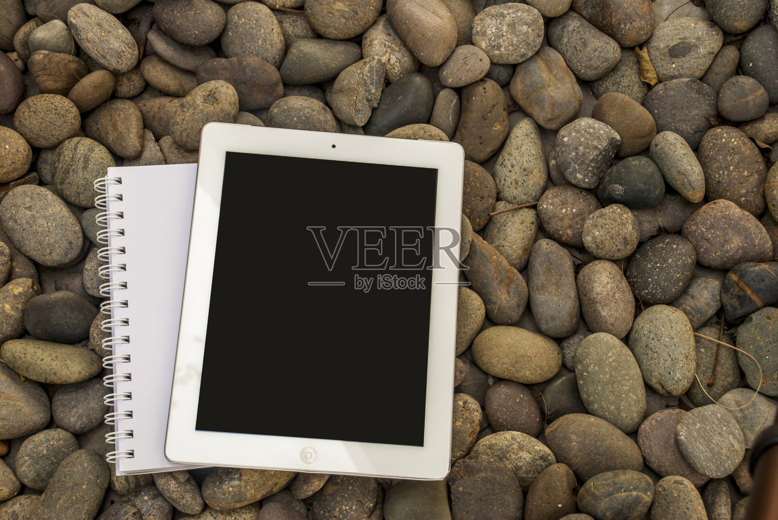 平板电脑和笔记本放在一堆石头上照片摄影图片