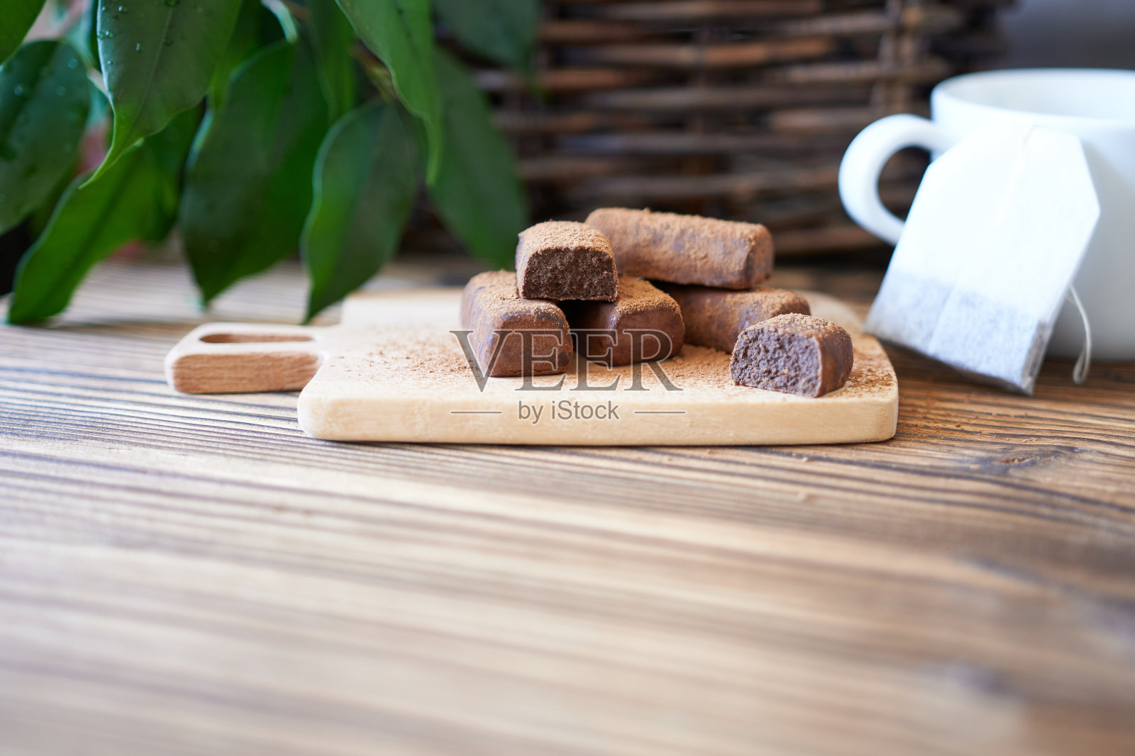 巧克力，一袋茶和一个白色的马克杯放在厨房的桌子上。这个概念就是早餐。照片摄影图片