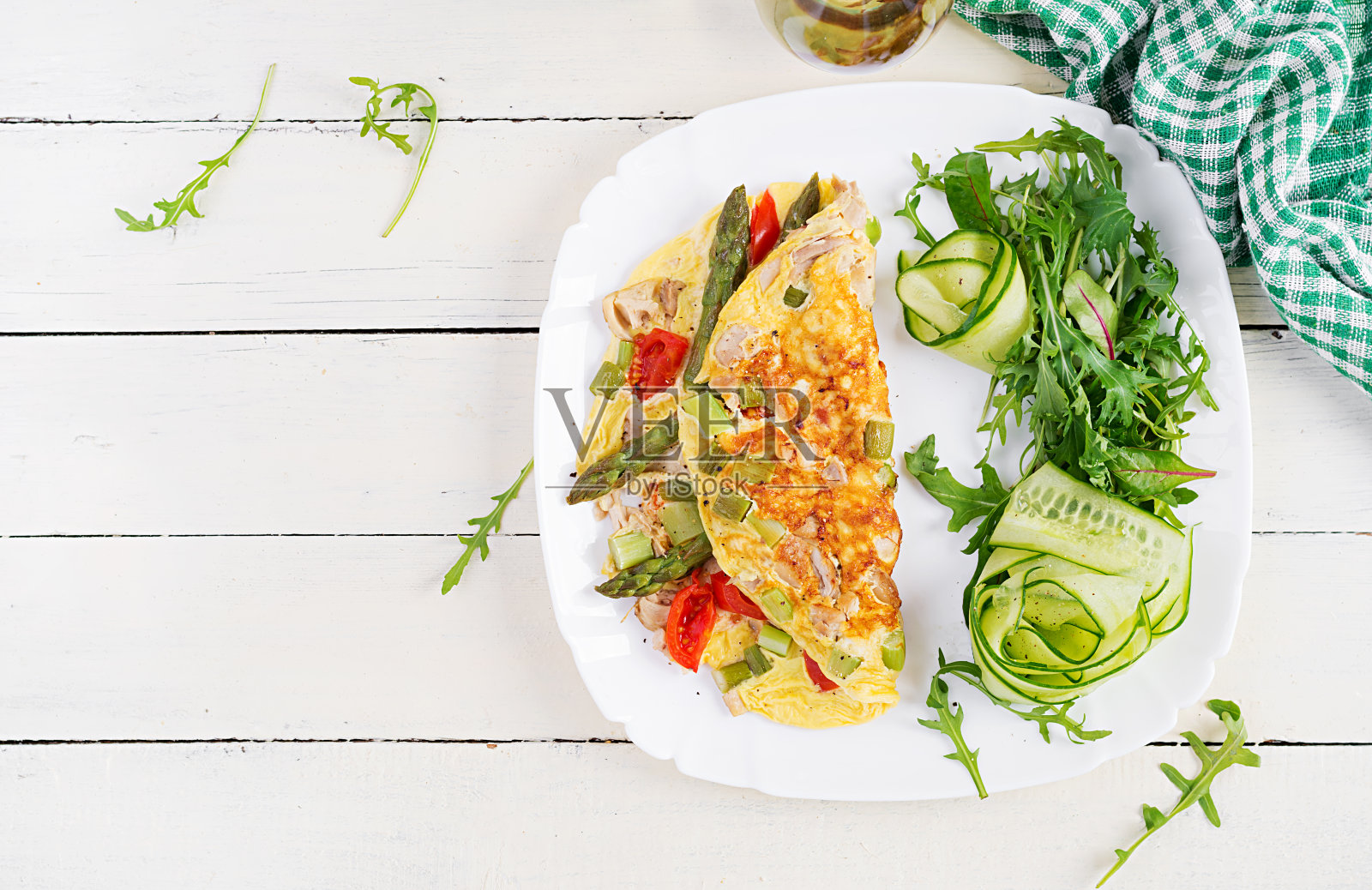 酮的早餐。白色木桌上的煎蛋卷配鸡柳、西红柿和芦笋。意大利菜肉馅煎蛋饼。生酮午餐。俯视图，开销，复制空间照片摄影图片