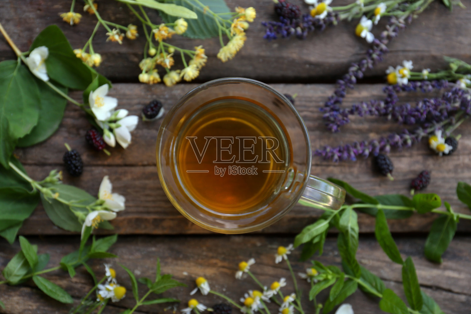 一杯热腾腾的香茗和各种新鲜的草药放在木桌上，平放照片摄影图片