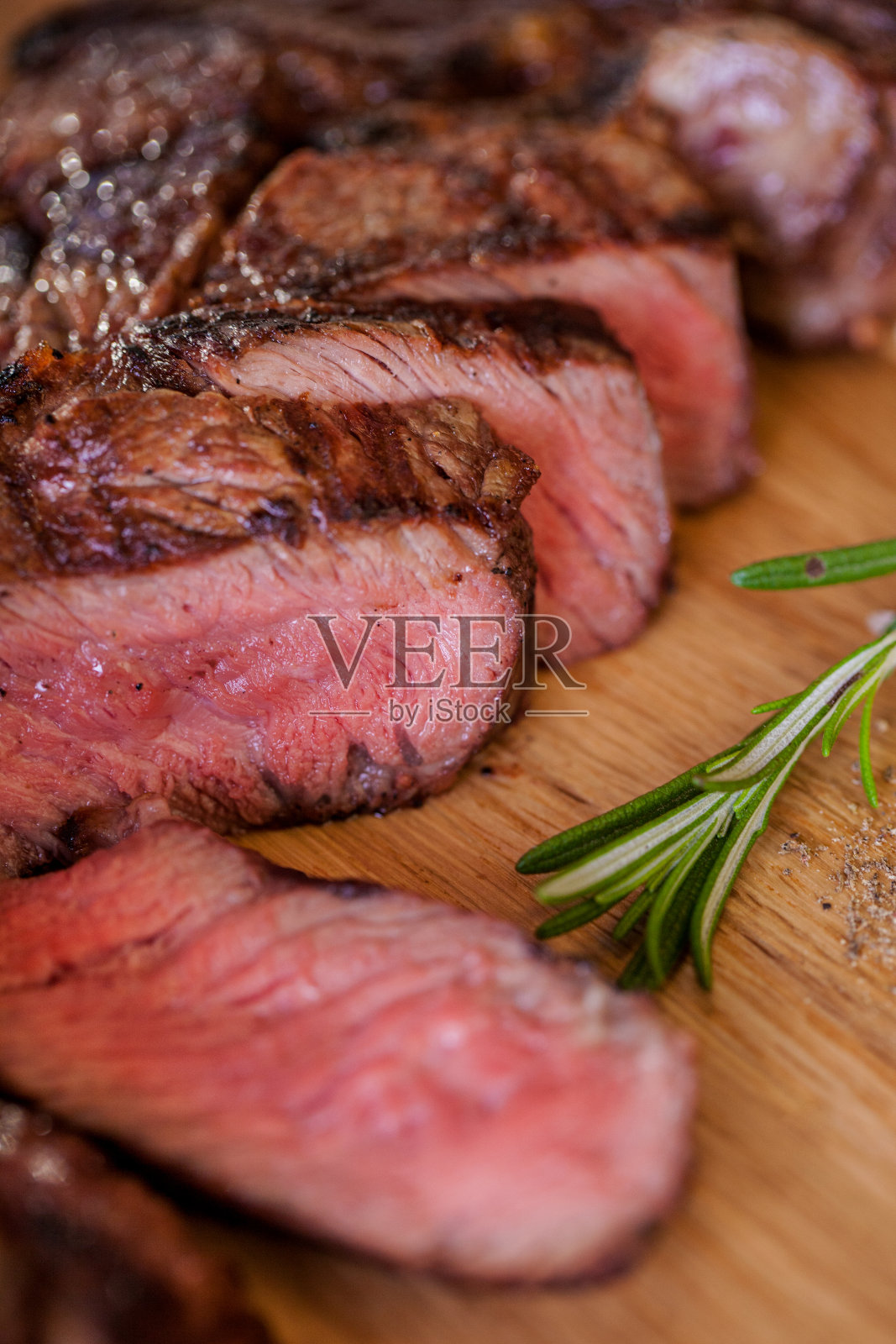烤猪肉牛排片配上一小枝迷迭香，胡椒和盐，炸面包片放在木板上。水平方向照片摄影图片