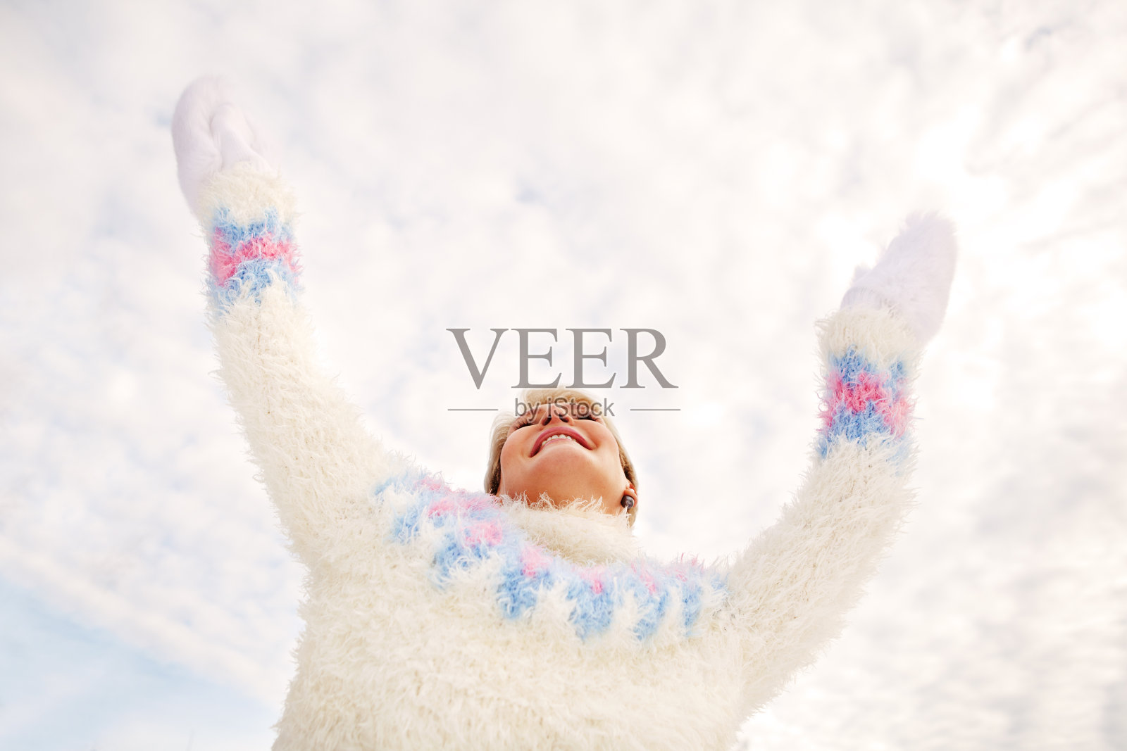 穿冬装的快乐女人举手享受阳光与白云天空中照片摄影图片