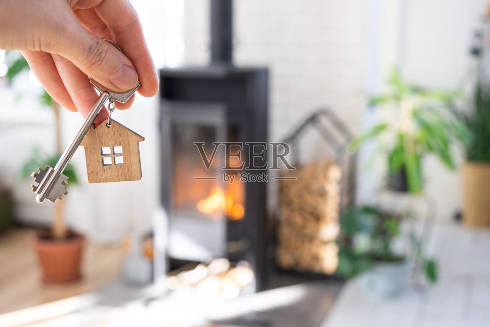 钥匙的房子与钥匙链对背景的壁炉火炉与火和柴火。舒适的家。建筑，设计，工程，搬新房，抵押，租赁和购买房地产照片摄影图片