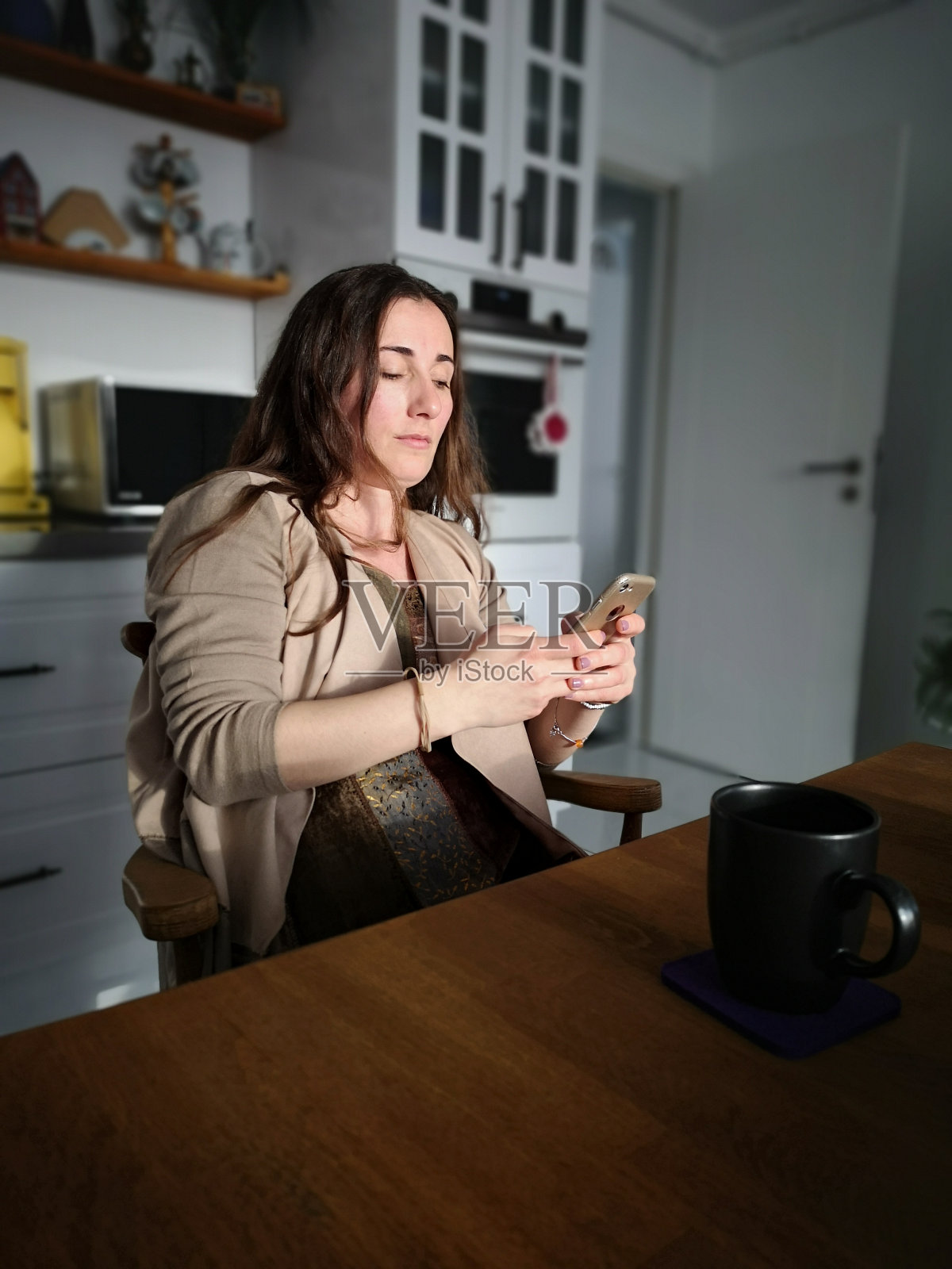 女人坐在厨房的桌子上用手机照片摄影图片