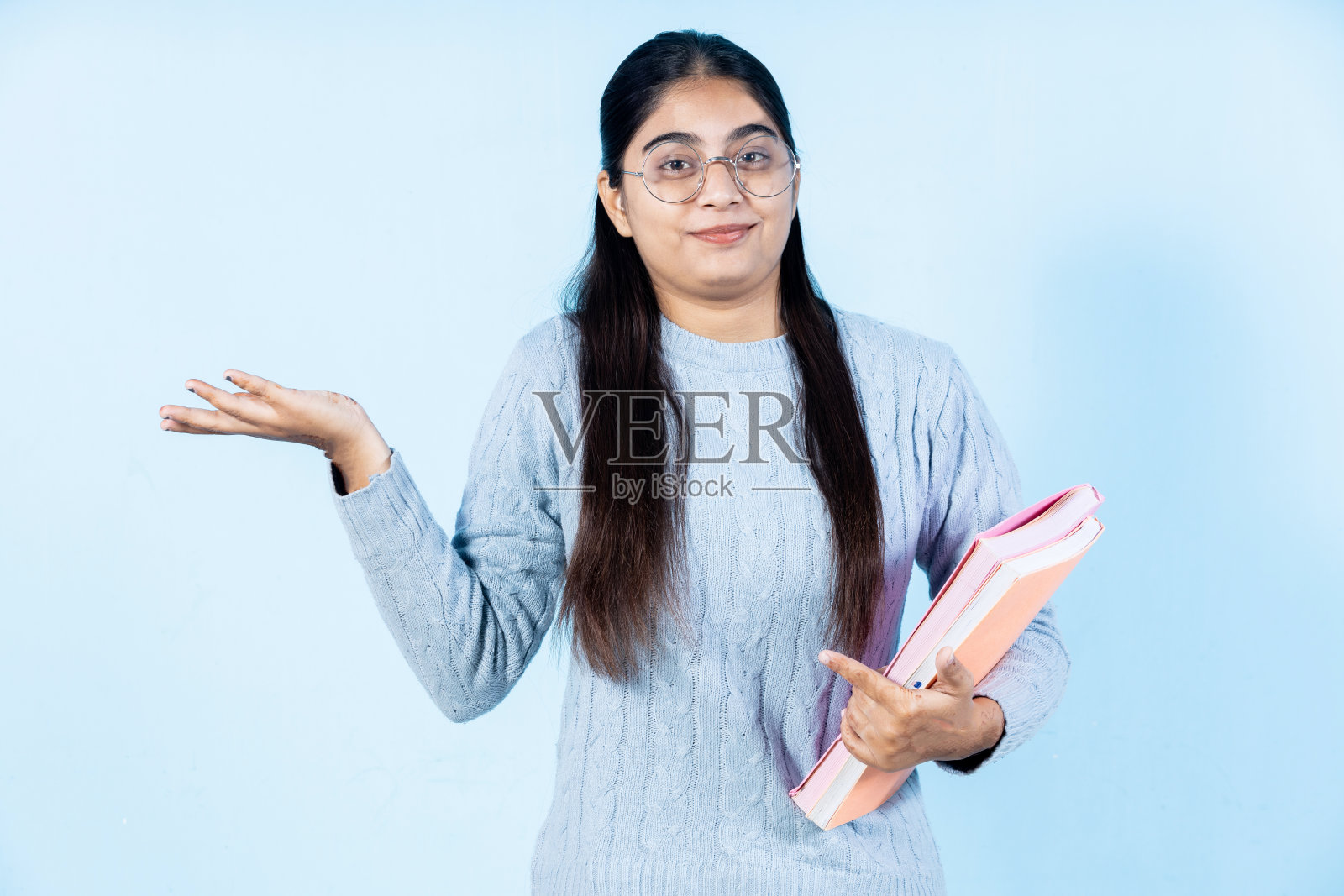 女十几岁的学生拿着书和给予表达照片摄影图片