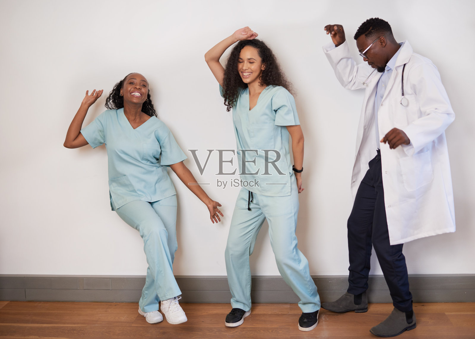 三名医疗专业人员在休息时跳舞，医生玩得很开心照片摄影图片