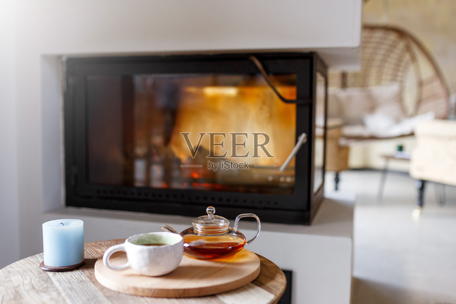 斯堪的纳维亚式的室内风格，温暖的壁炉，前面有扶手椅，自然光线从窗户射进来。零废物家居概念。木制家具。茶水上桌照片摄影图片