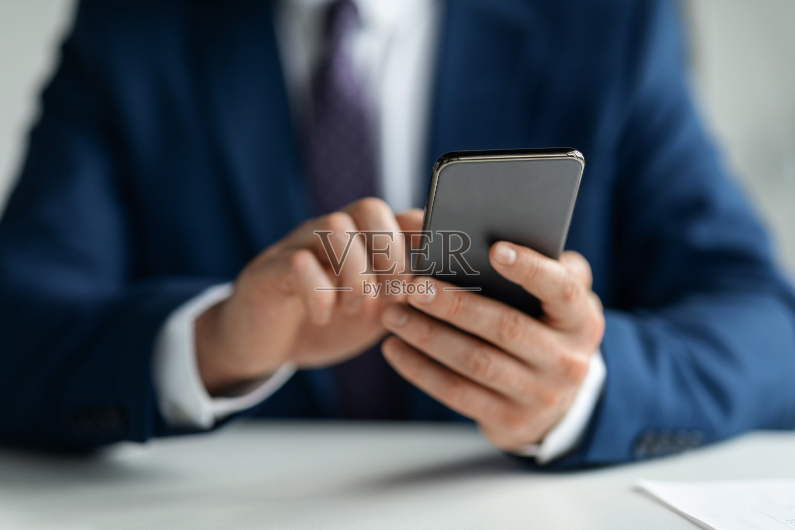 西装革履的商人在工作场所使用智能手机照片摄影图片