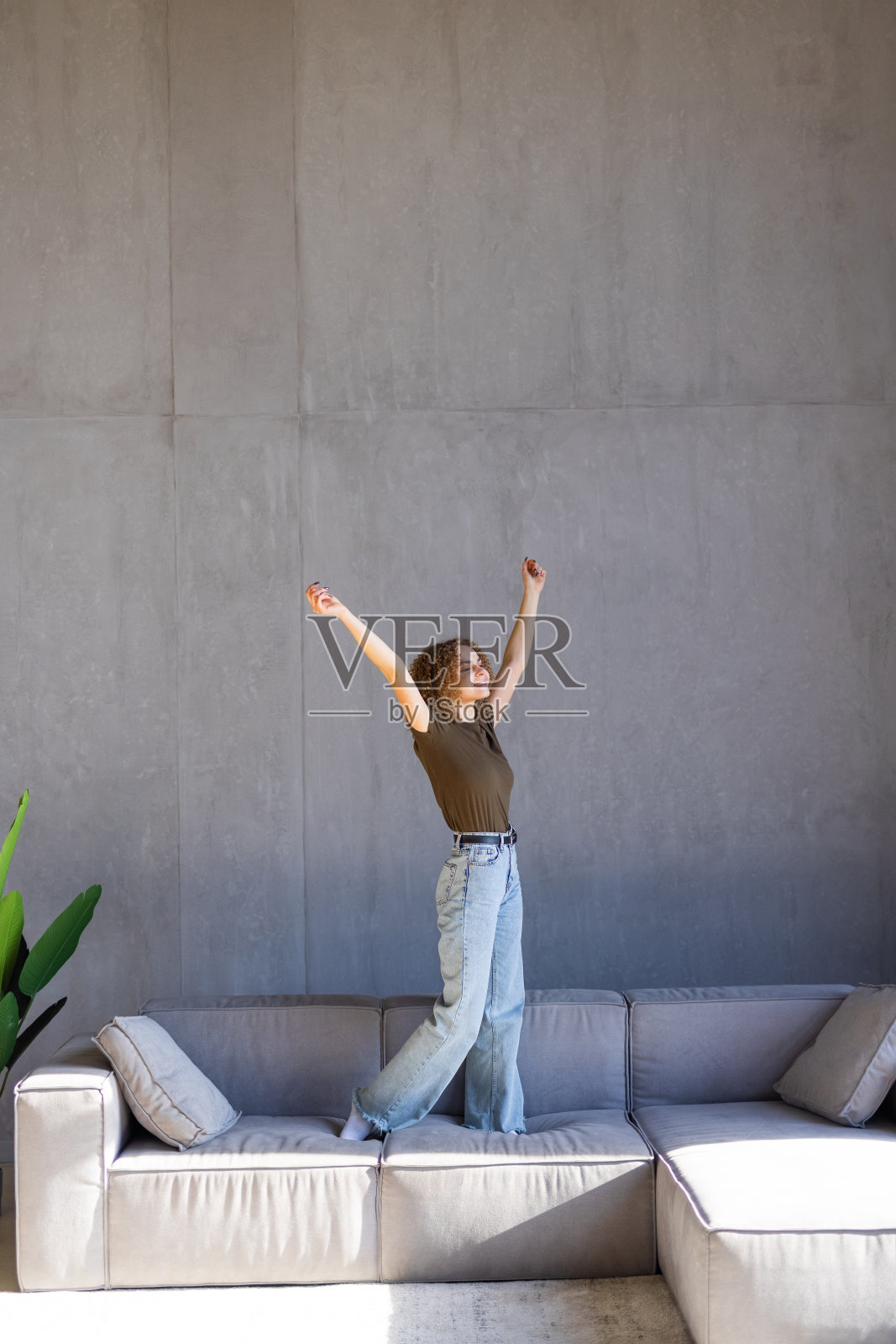 积极的年轻女子听着音乐，在轻现代客厅的沙发上跳舞照片摄影图片