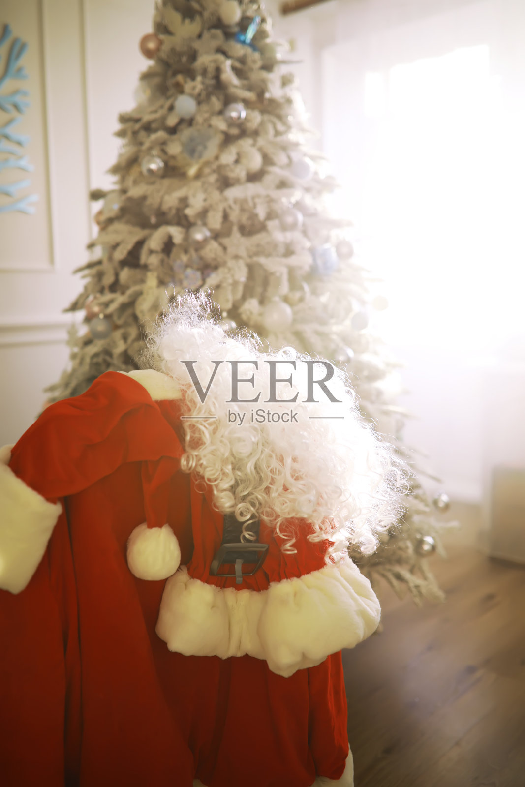 圣诞老人服装挂在白色的房间。椅子和圣诞老人送的衣服照片摄影图片