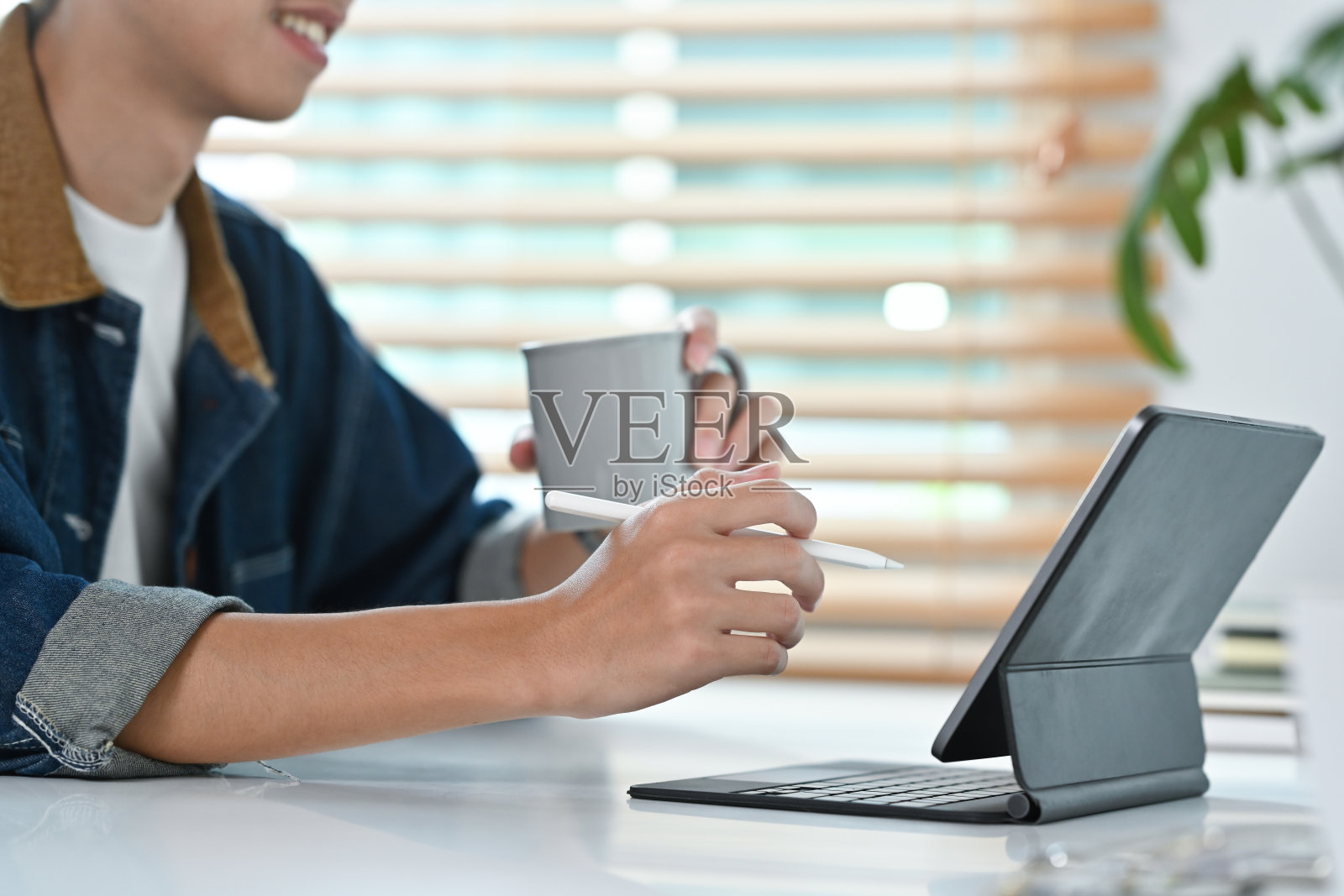 年轻的潮人拿着一杯咖啡，在办公室的数字平板电脑上进行设计项目。照片摄影图片