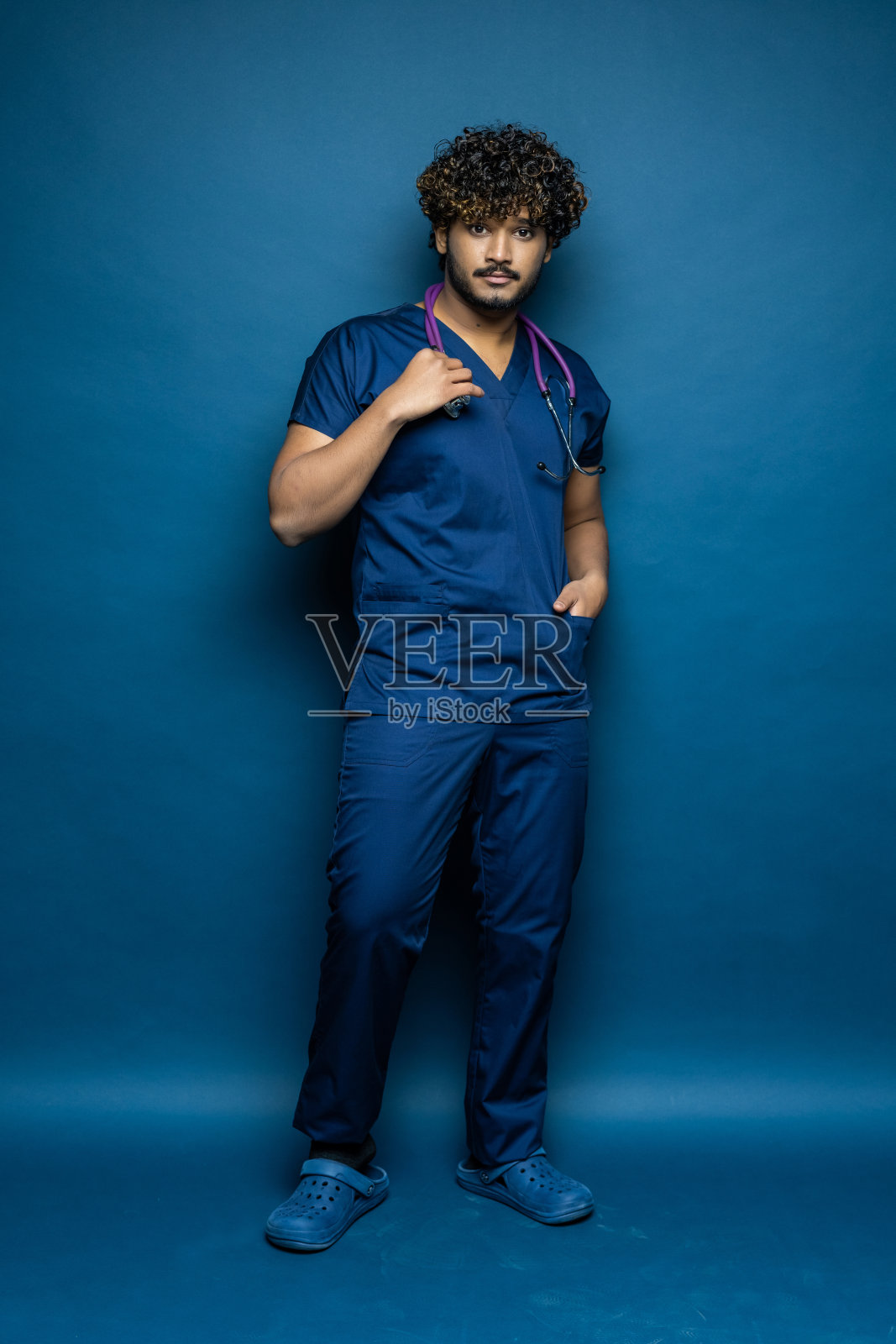 蓝色背景上带有听诊器的医生的全身肖像照片摄影图片