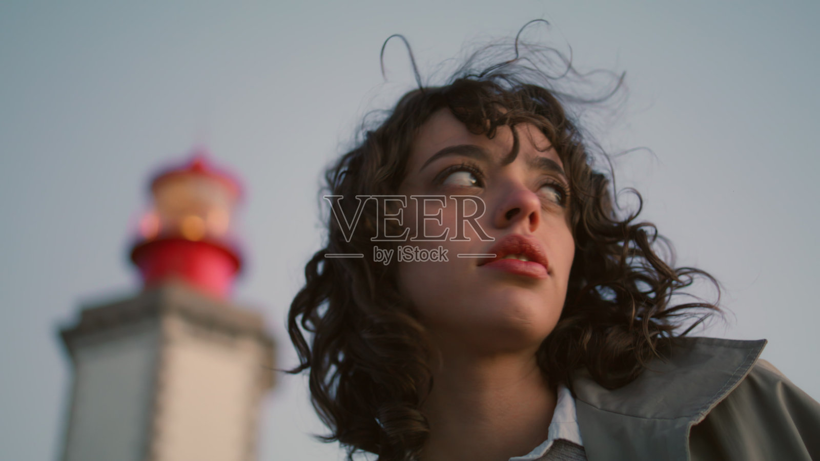 肖像担心女孩摆姿势在夜间灯塔的观点。体贴的卷发女人照片摄影图片