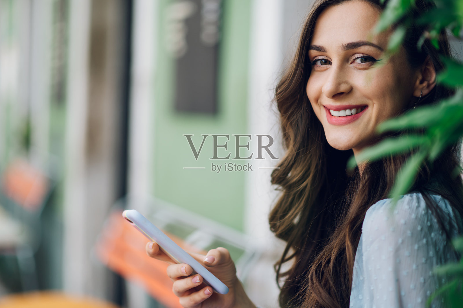 一个美丽的女人坐在街头咖啡馆和使用智能手机的肖像照片摄影图片