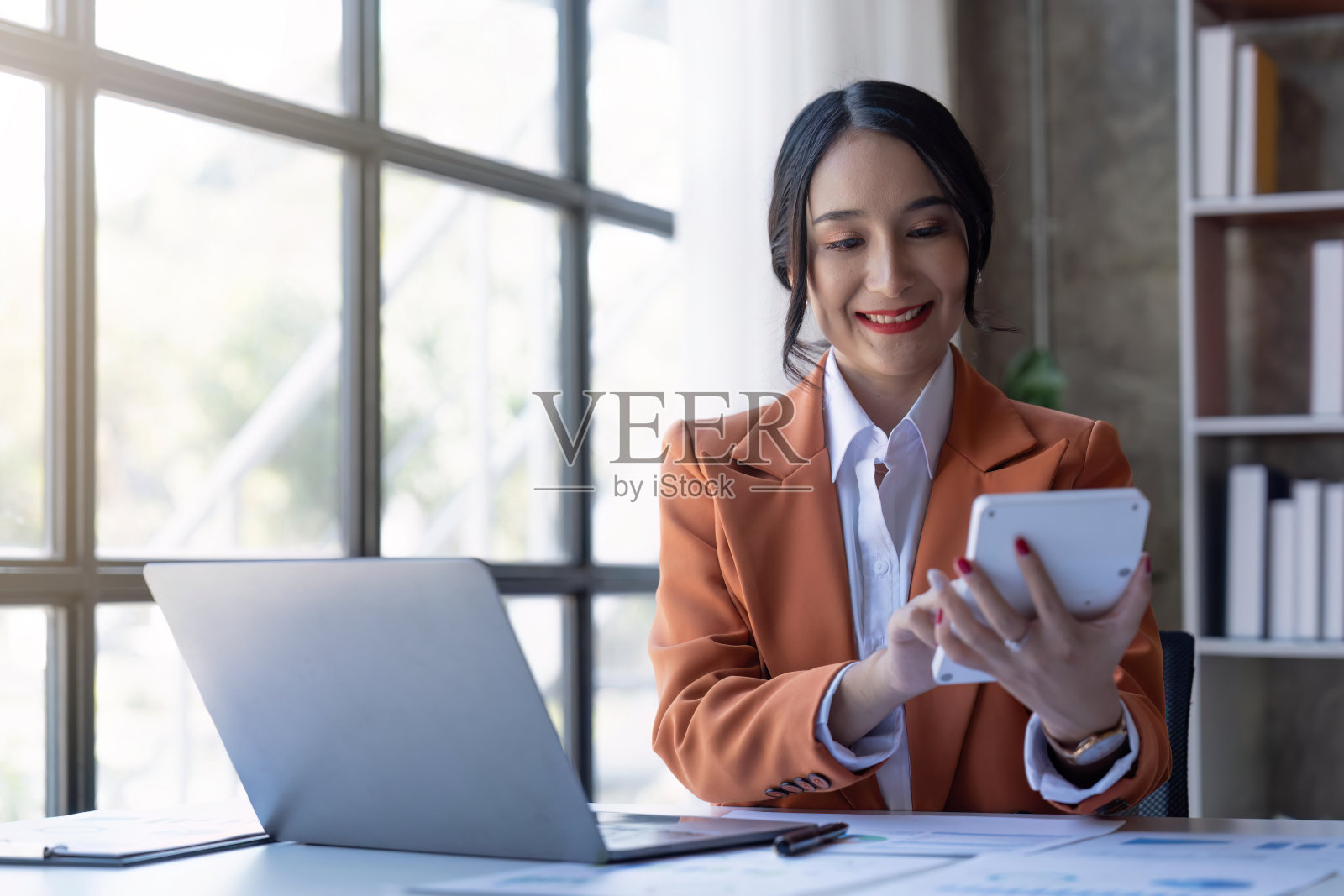 亚洲商业女性使用计算器和笔记本电脑在办公桌上做数学、金融、税务、报告、会计、统计和分析研究概念照片摄影图片