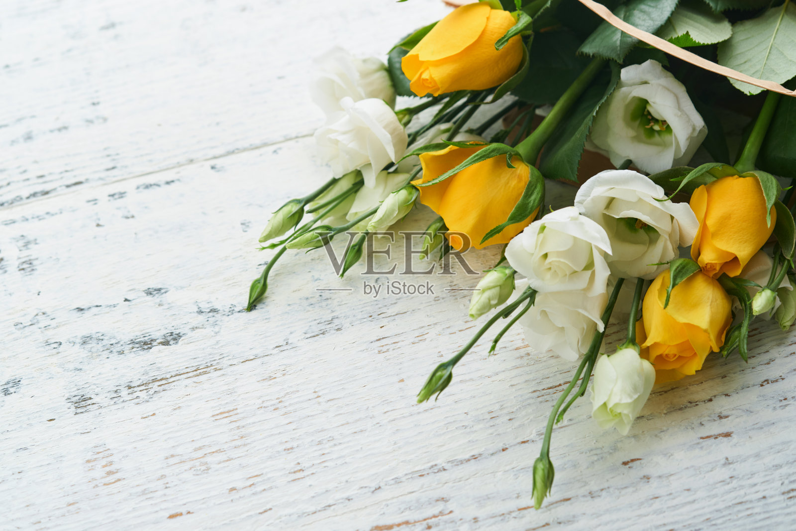 复活节的概念。一束新鲜的白色和黄色玫瑰纸袋在旧的白色木制背景。逾越节庆祝概念。母亲节的概念，妇女节，春天的背景。俯视图照片摄影图片
