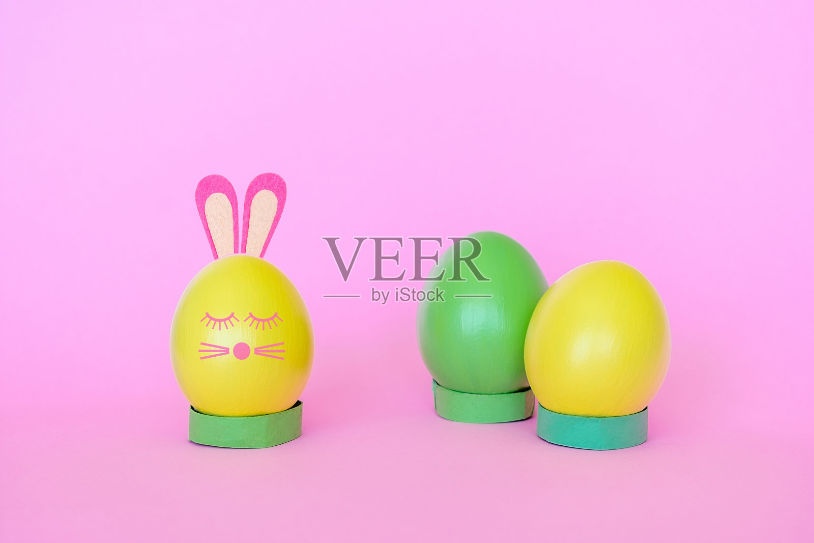 黄色和绿色的复活节彩蛋，装饰成兔子的形状。照片摄影图片