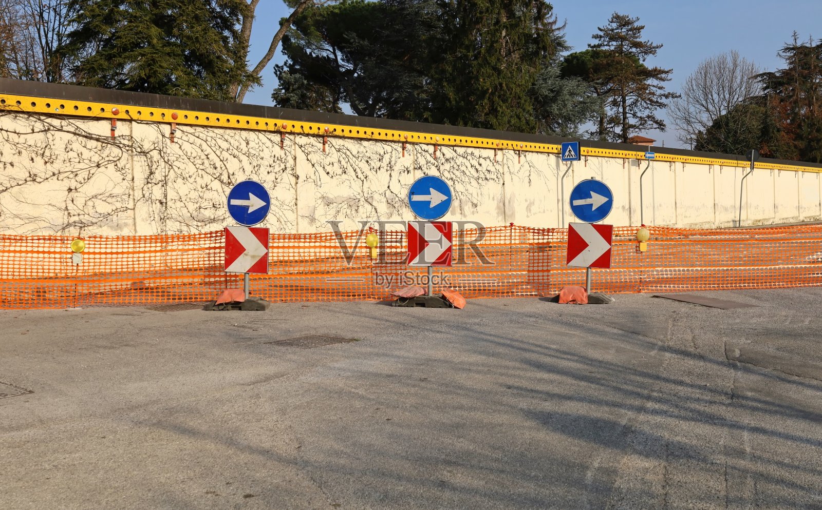 在临时封闭道路前的塑料屏障前设有若干定向路标和警示灯。照片摄影图片