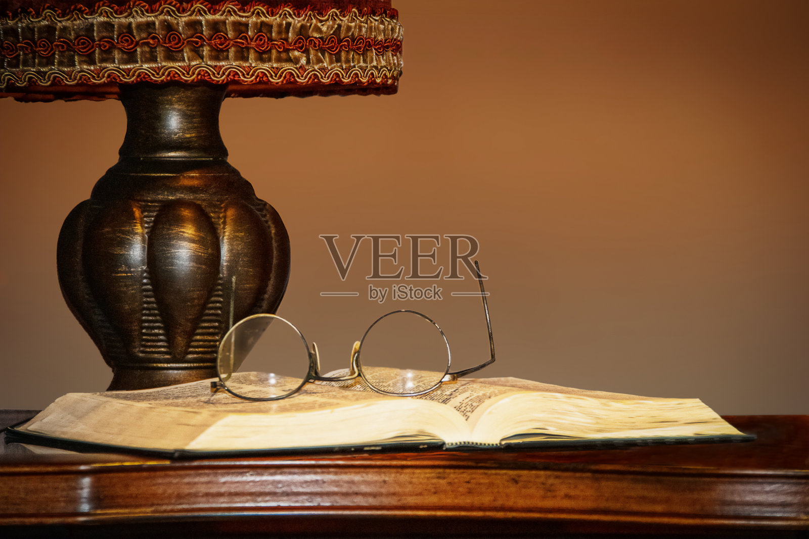 老式的台灯在桌子上，旁边是打开的书，上面放着眼镜——复印的空间照片摄影图片