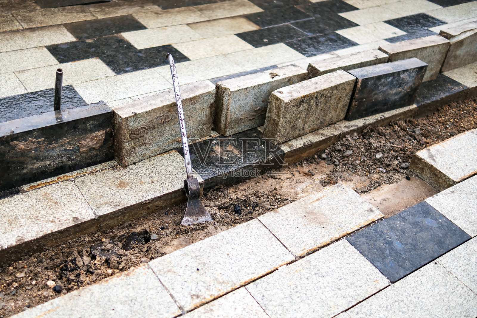 金属管焊接在斧头上。修补人行道上的瓦片。照片摄影图片