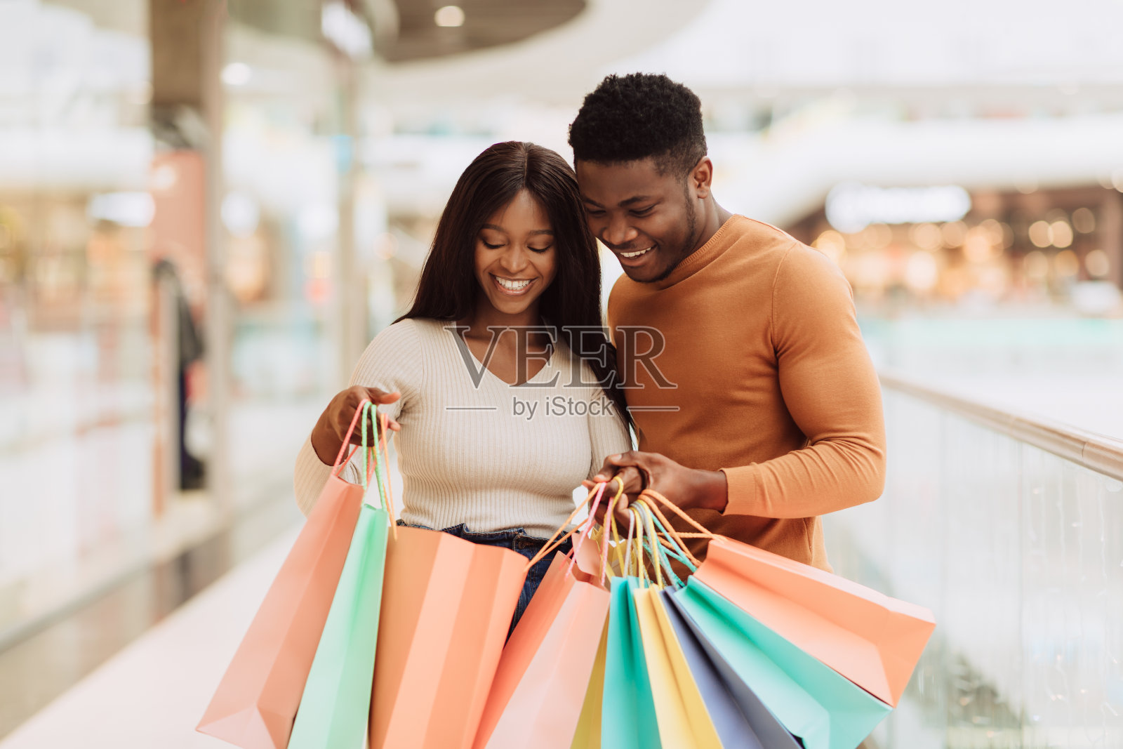 快乐的黑人夫妇拿着购物袋往里看照片摄影图片