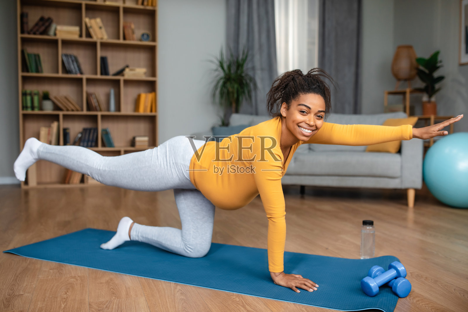 孕妇锻炼。快乐的漂亮的年轻非裔美国女人练习瑜伽独自在垫子上照片摄影图片